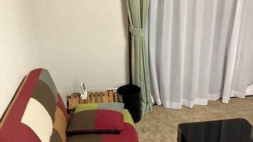 A room with a colorful sofa, a small table, and a window with curtains.