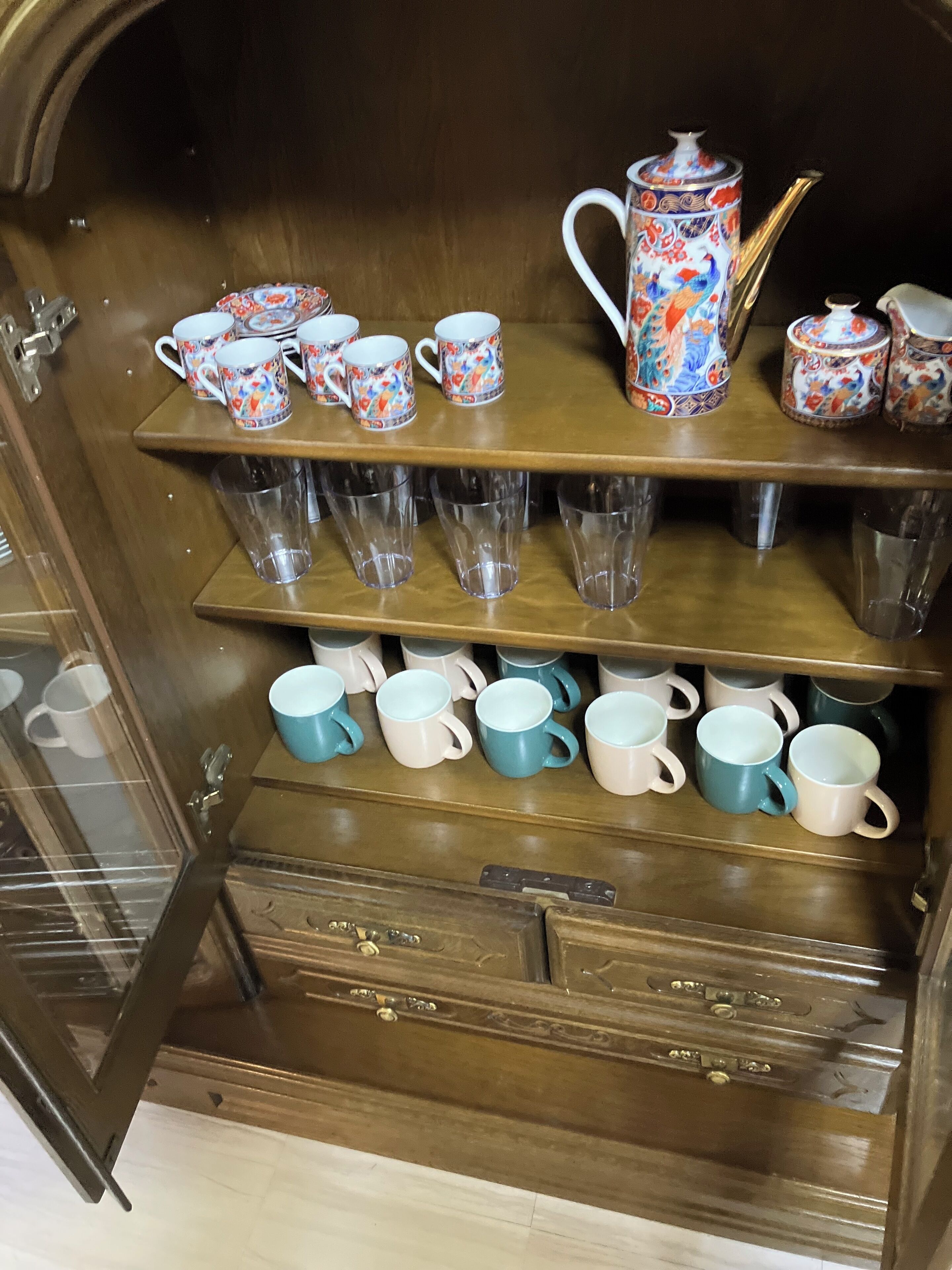 A wooden cabinet with shelves holding various mugs and glasses.