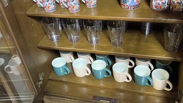 A wooden cabinet with shelves holding various mugs and glasses.