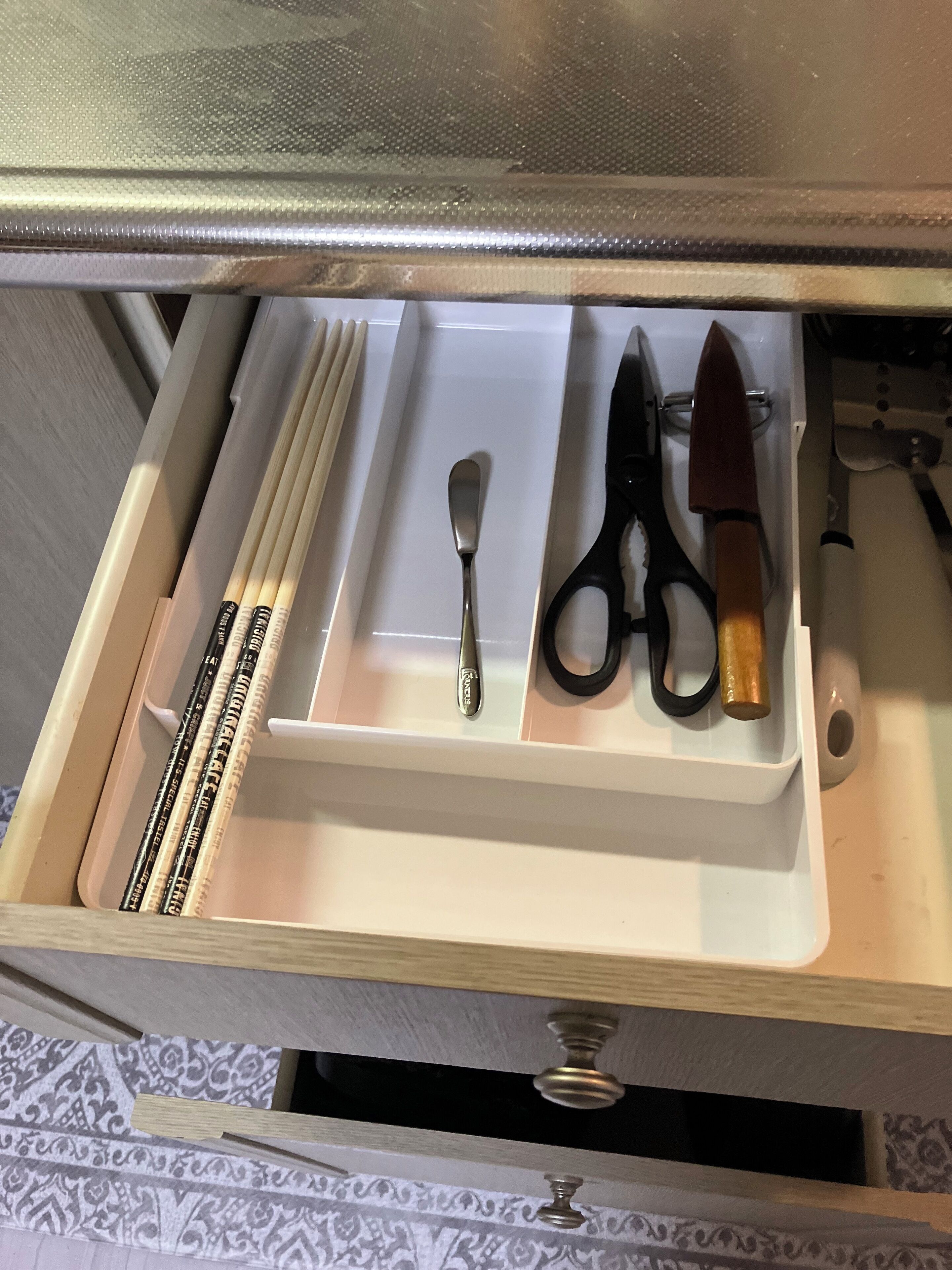 A drawer with a spoon, scissors, and a knife.