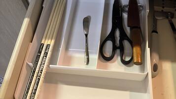 A drawer with a spoon, scissors, and a knife.