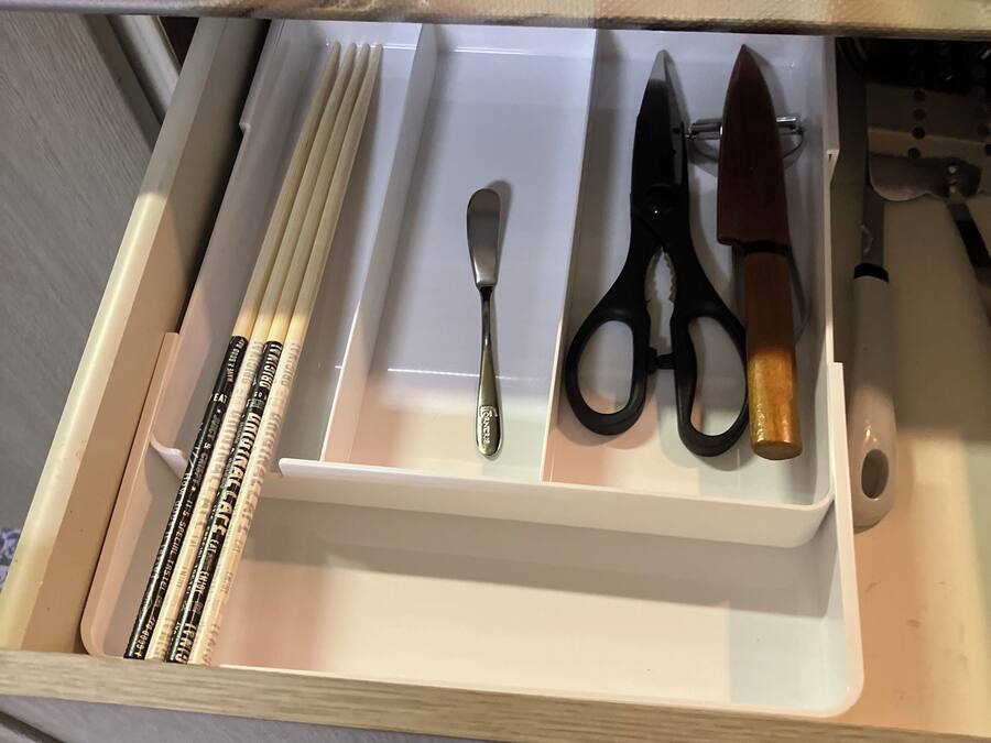 A drawer with a spoon, scissors, and a knife.