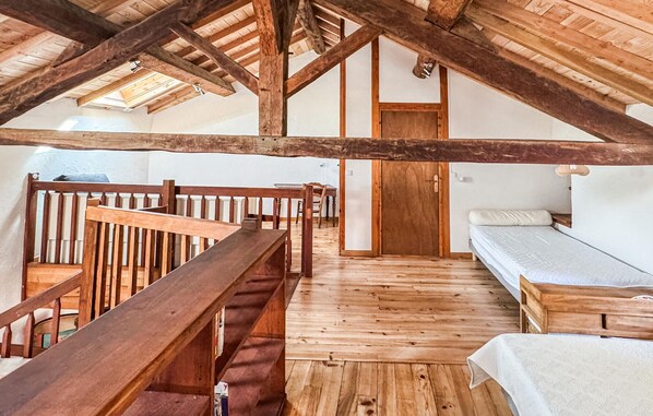 Een loft-achtig vertrek met een houten trap, een bed en een kleine tafel.