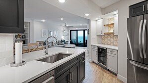 Una cocina moderna con una isla grande, electrodomésticos de acero inoxidable y vistas al exterior.