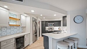 Una cocina moderna con una isla central, electrodomésticos de acero inoxidable y un reloj en la pared.