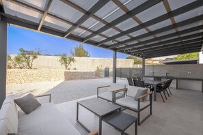 Relax in style with a comfortable seating area, perfect for casual dining or unwinding, featuring a barbecue grill and sheltered by a metal roof.
