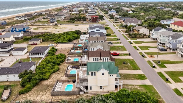 A coastal residential area with houses, a beach, and a road. - 4744- Sandy Beaches, a spacious home in the heart of Kill Devil Hills! (Kitty Hawk)