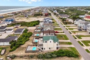 A coastal residential area with houses, a beach, and a road. - 4744- Sandy Beaches, a spacious home in the heart of Kill Devil Hills! (Kitty Hawk)