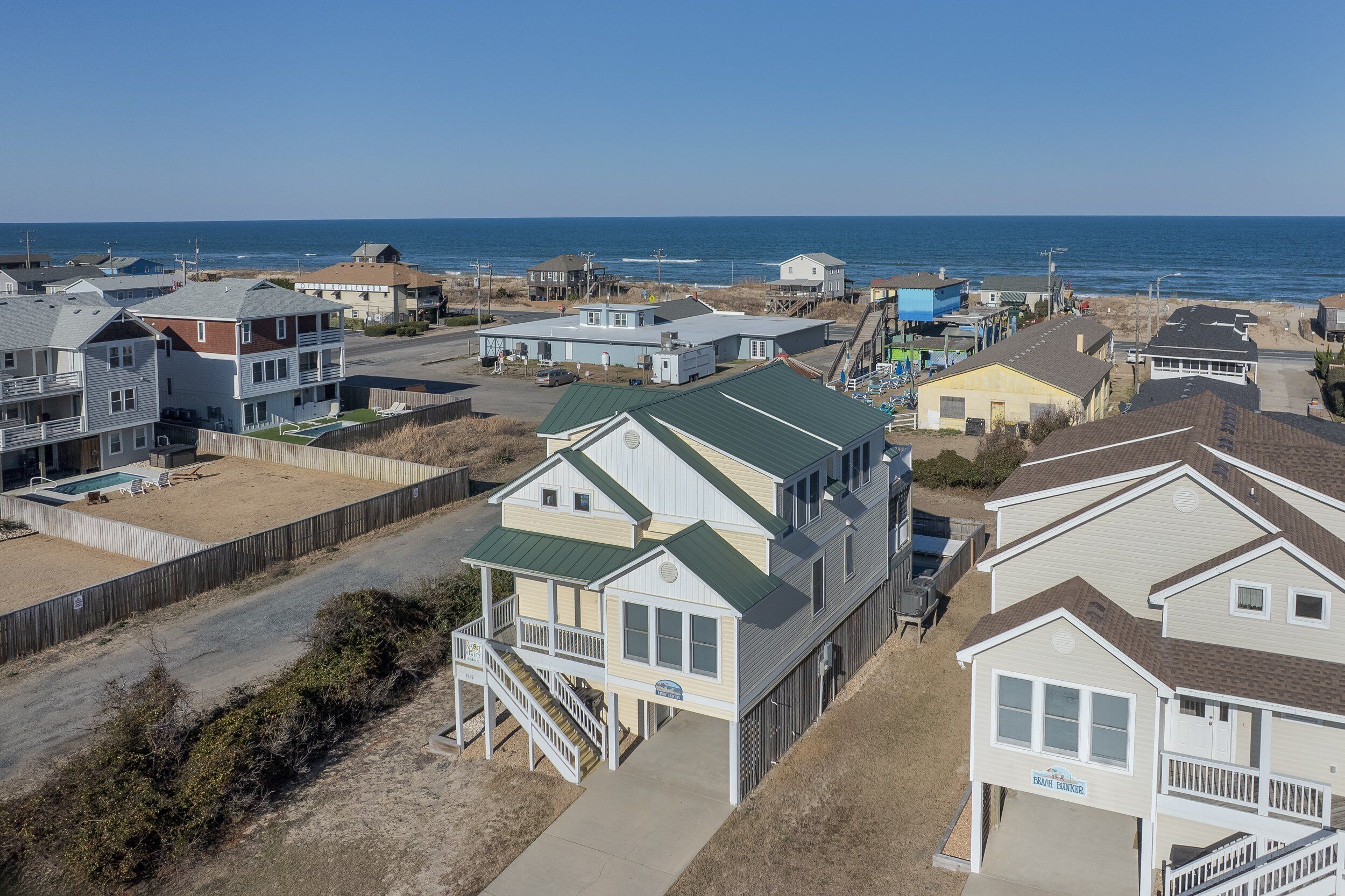 Un quartier résidentiel situé sur la côte, avec des maisons, une plage et une vue dégagée sur l’océan.