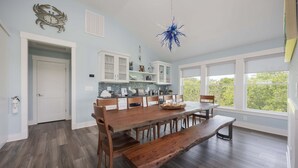 Un'ampia sala da pranzo con un grande tavolo di legno, panche e un lampadario blu appeso al soffitto.