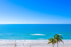 A beach with clear blue water, white sand, and palm trees.