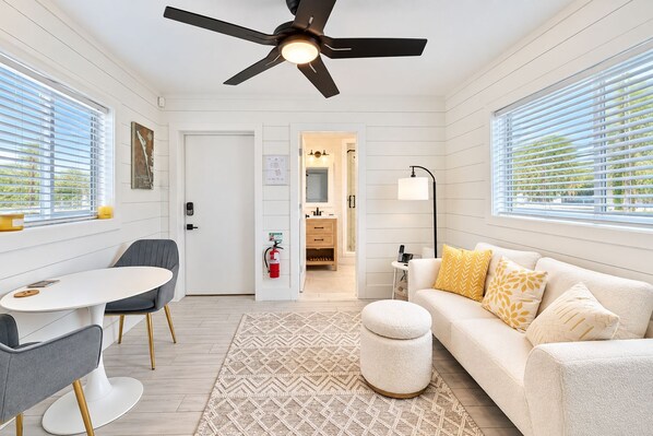 A modern living room with a ceiling fan, a sofa with patterned cushions, a coffee table, and a side table.