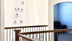 A staircase with a wooden handrail and black metal balusters, leading to a room with a blue wall and a black leather sofa. - Zion`s Poolside Paradise (La Verkin)