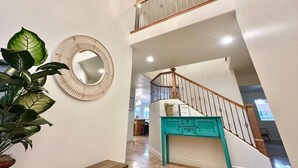 A spacious hallway with a wooden bench, a round mirror, and a staircase with teal accents. - Zion`s Poolside Paradise (La Verkin)