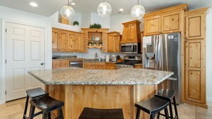 A kitchen with wooden cabinets, granite countertops, stainless steel appliances, and pendant lighting. - Zion`s Poolside Paradise (La Verkin)