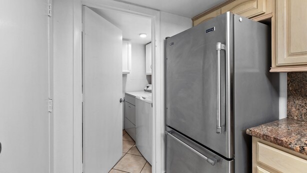 Una cocina con refrigerador de acero inoxidable, gabinetes blancos y encimera de granito.