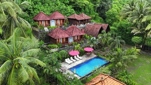 A resort with multiple bungalow-style buildings, a swimming pool, and lush tropical vegetation. - Coconut Hill Cottage (Penida Island)