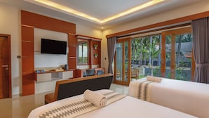 A modern hotel room with a large bed, a desk, a flat-screen TV, and a balcony with a view of palm trees. - Coconut Hill Cottage (Penida Island)