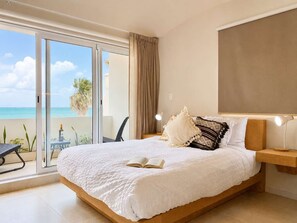 Ein Schlafzimmer mit einem großen Bett, einem Nachttisch, einer Leselampe und Meerblick durch eine Schiebetür.