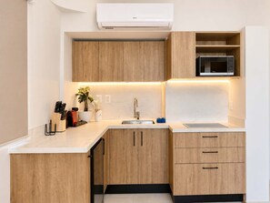 A modern kitchen with wooden cabinets, a built-in microwave, and a countertop with a sink.