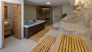 A modern bathroom with a wooden vanity, a freestanding bathtub, and a stone accent wall. - Amazing home in Slivno Ravno with sauna (Slivno Ravno)