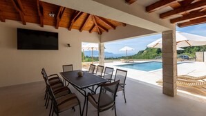 An outdoor patio with a pool, dining table, and chairs. - Amazing home in Slivno Ravno with sauna (Slivno Ravno)