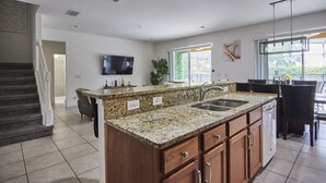 A modern kitchen with granite countertops, a built-in dishwasher, and a large window providing natural light. - Luxury Disney Getaway with Pool (Davenport)