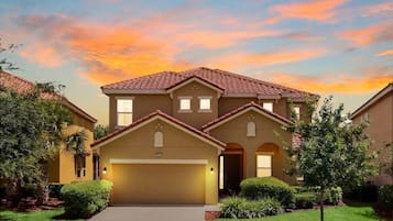 Gracie Orlando Getaway at sunset, with the front exterior and driveway illuminated.