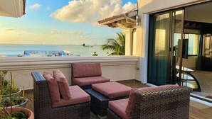 A balcony with wicker furniture, a view of the ocean, and a glass door leading to a room. - 4BR House | Hotel Zone | Beach & 3 Pools (Cancún)