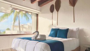 A bedroom with a bed, pillows, a swan decoration, a window with a view, and wall art. - 4BR House | Hotel Zone | Beach & 3 Pools (Cancún)