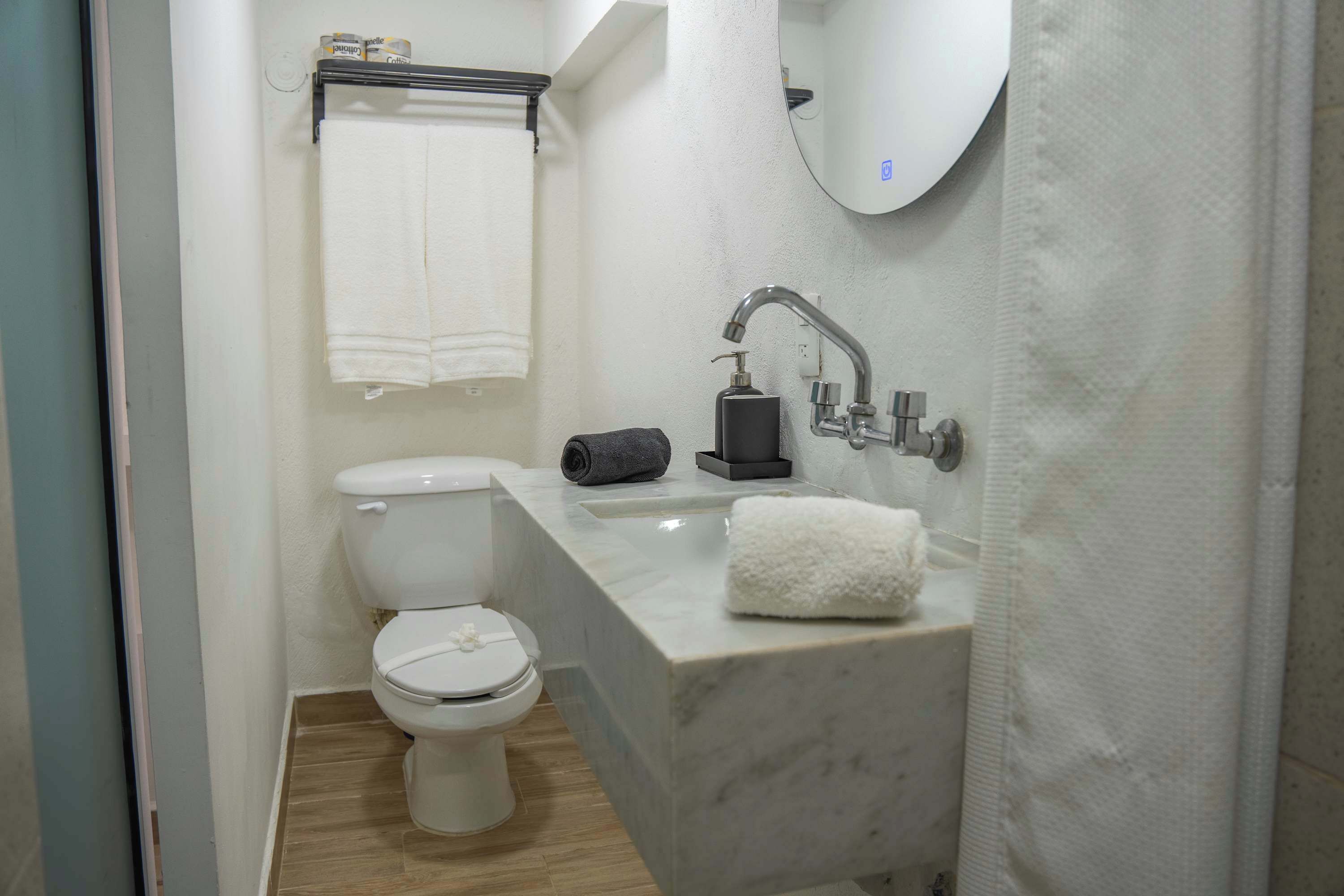 A bathroom with a toilet, a sink, a mirror, and a towel rack.
