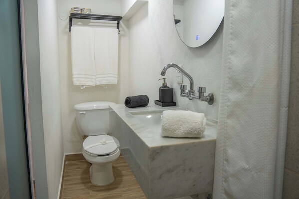 A bathroom with a toilet, a sink, a mirror, and a towel rack.