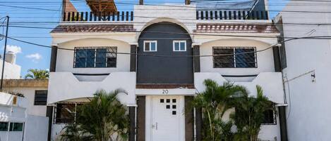 Um edifício de dois andares com entrada central, porta de garagem e o número 20 na fachada.