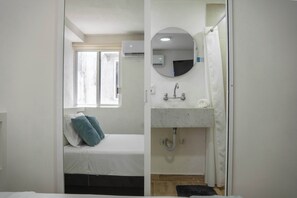 A bedroom with a bed, a window, a built-in sink, and a mirror.