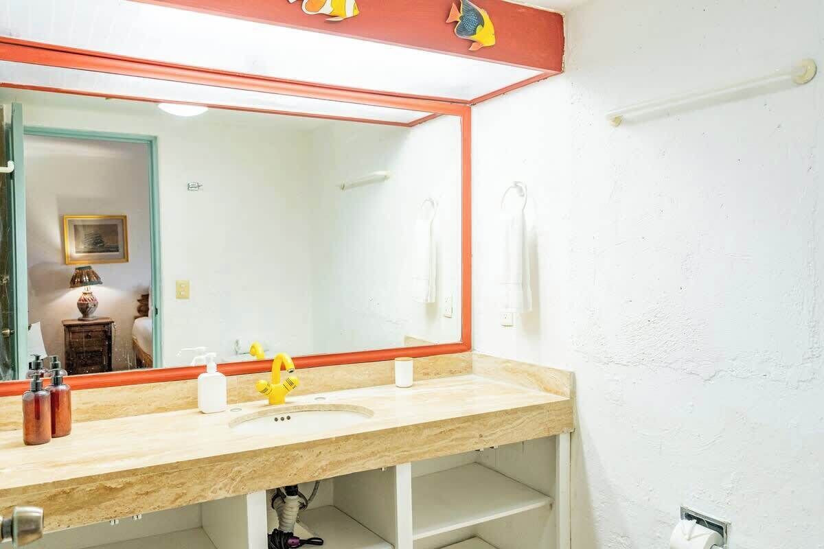 A bathroom with a large mirror, a sink, and a toilet.