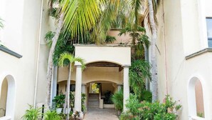 A covered outdoor area with a central pathway, surrounded by palm trees and potted plants. - 2BR Cancun Hotel Zone: Pool, Walk to the Beach (Cancún)