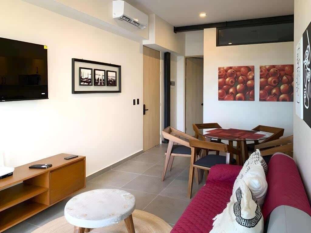 Un salon comprenant un canapé, une table basse, un téléviseur et un coin repas avec des chaises et une table.