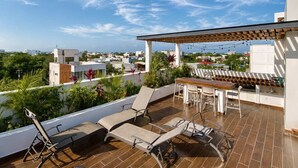 A rooftop terrace with lounge chairs, a table, and a pergola. - 2BR Apt + Rooftop Pool | Steps to 5th Avenue (Playa del Carmen)