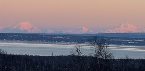 A panoramic view of a snowy landscape with mountains in the background and a frozen body of water in the foreground.