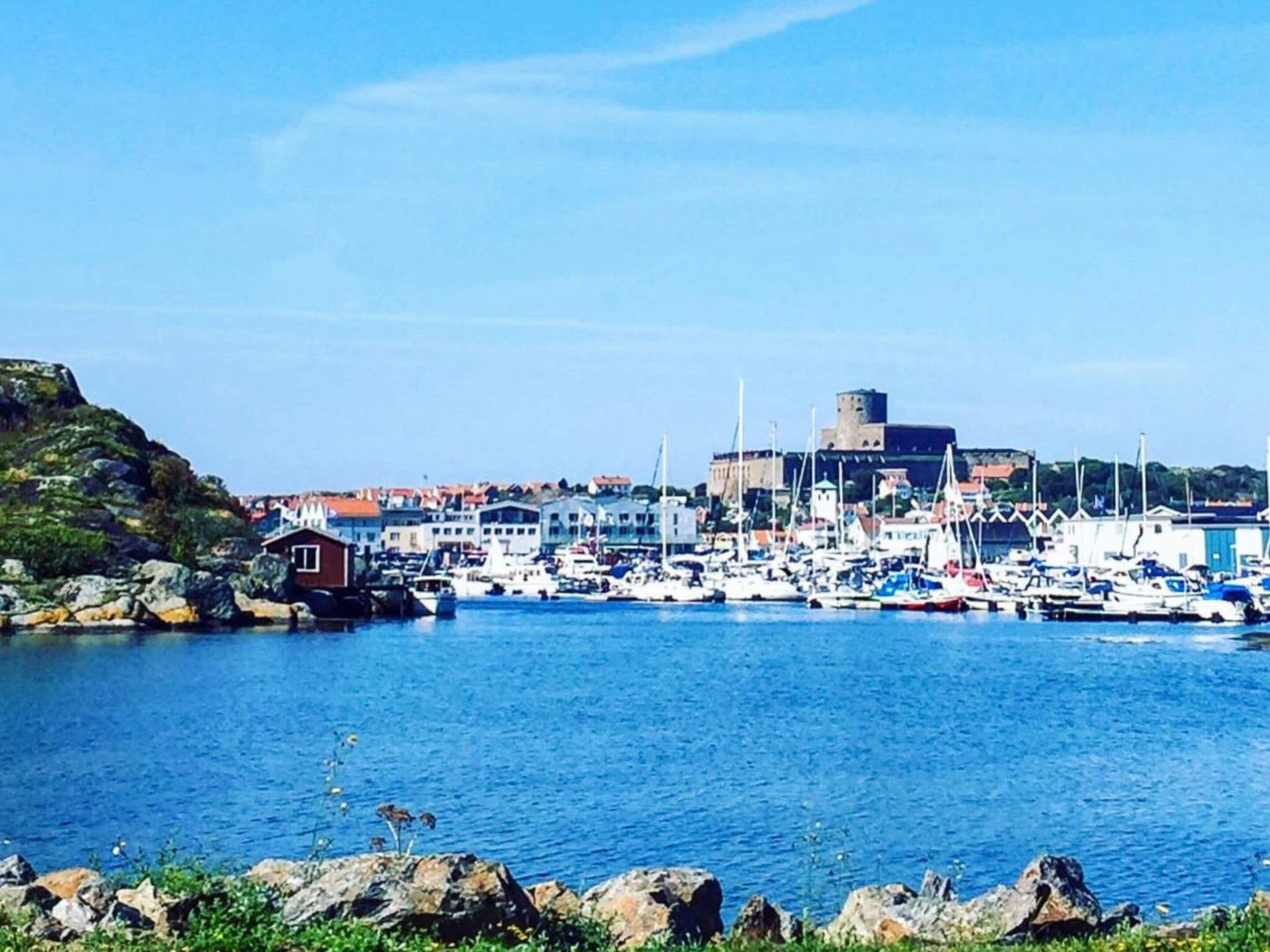 A coastal town with a marina, rocky shoreline, and a prominent building with a tower.