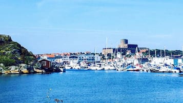 A coastal town with a marina, rocky shoreline, and a prominent building with a tower.