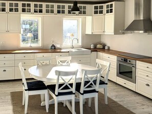 A kitchen with white cabinetry, a central island, and an oven. - 5 Star Holiday Home in Marstrand (Marstrand)