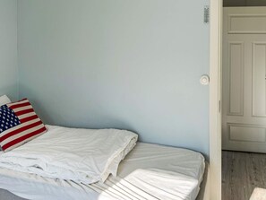 A bed with white bedding and a pillow featuring the American flag design. - 5 Star Holiday Home in Marstrand (Marstrand)