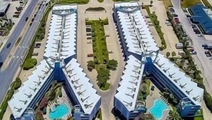 A coastal hotel with a central swimming pool, multiple parking areas, and a beach view. - Updated 1-bedroom on Galveston’s seawall with ocean view, children’s bunks, wifi (Galveston)