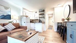 A compact living space with a kitchenette, a sofa, a coffee table, and a dining area with bar stools. - Updated 1-bedroom on Galveston’s seawall with ocean view, children’s bunks, wifi (Galveston)