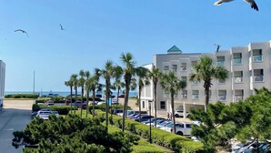 A coastal hotel with a parking lot, palm trees, and a view of the sea. - Updated 1-bedroom on Galveston’s seawall with ocean view, children’s bunks, wifi (Galveston)