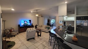 A modern living room with a television, sofa, and dining area. - Central Florida Pool Home (DeBary)