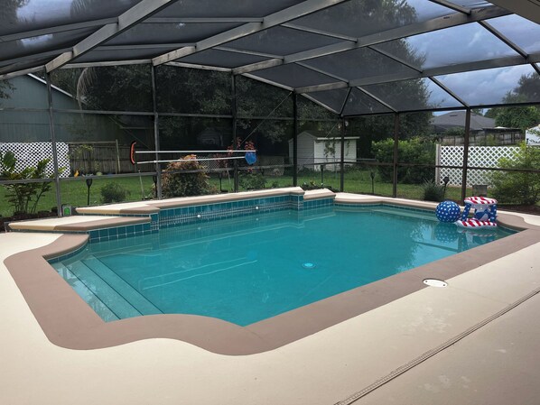 A swimming pool with a safety cover, surrounded by a deck and a fence. - Central Florida Pool Home (DeBary)