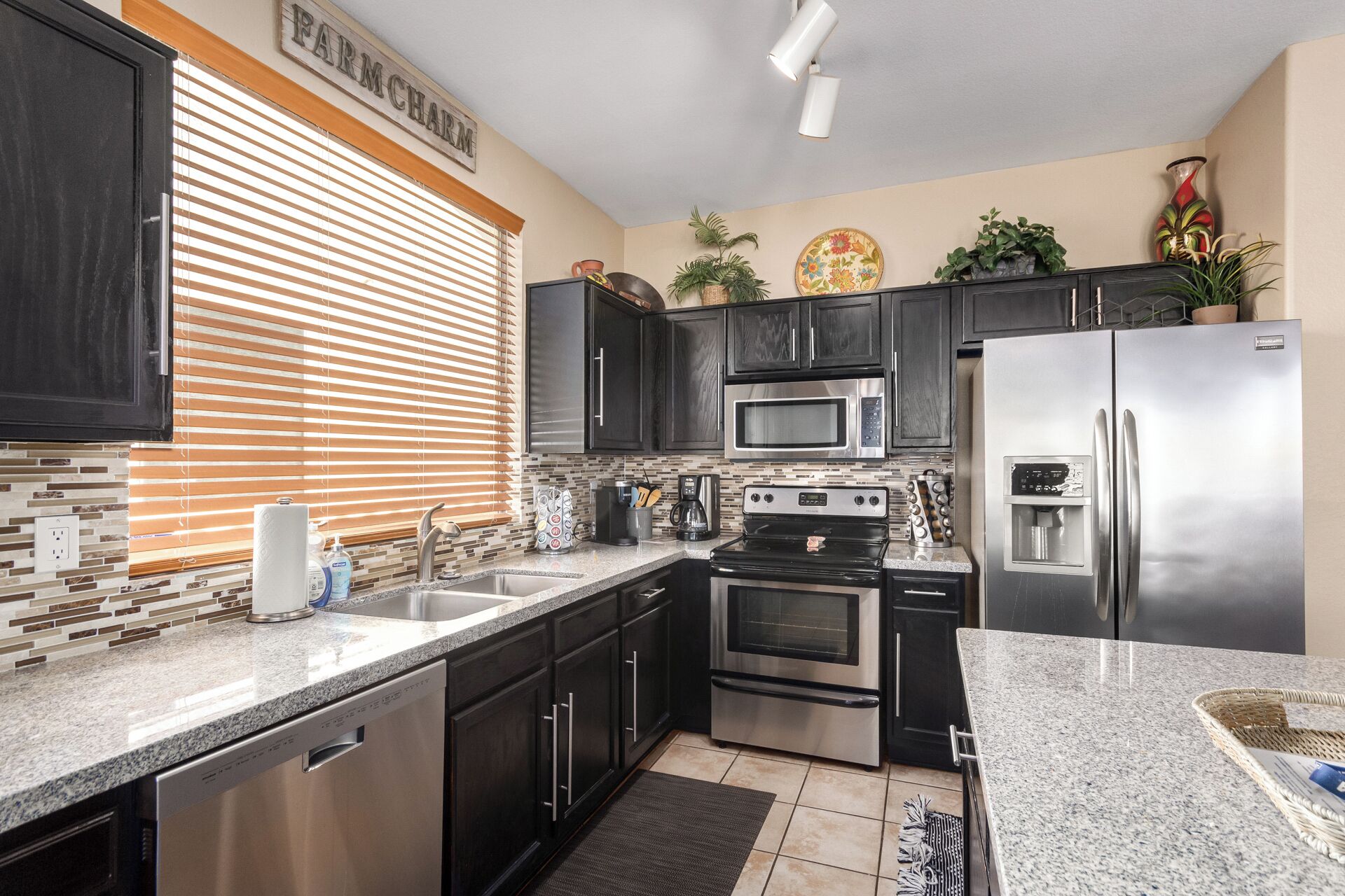 A modern kitchen with dark cabinets, stainless steel appliances, a microwave, oven, and refrigerator.