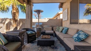 Un patio exterior con mobiliario de mimbre, una parrilla y una lámpara decorativa.